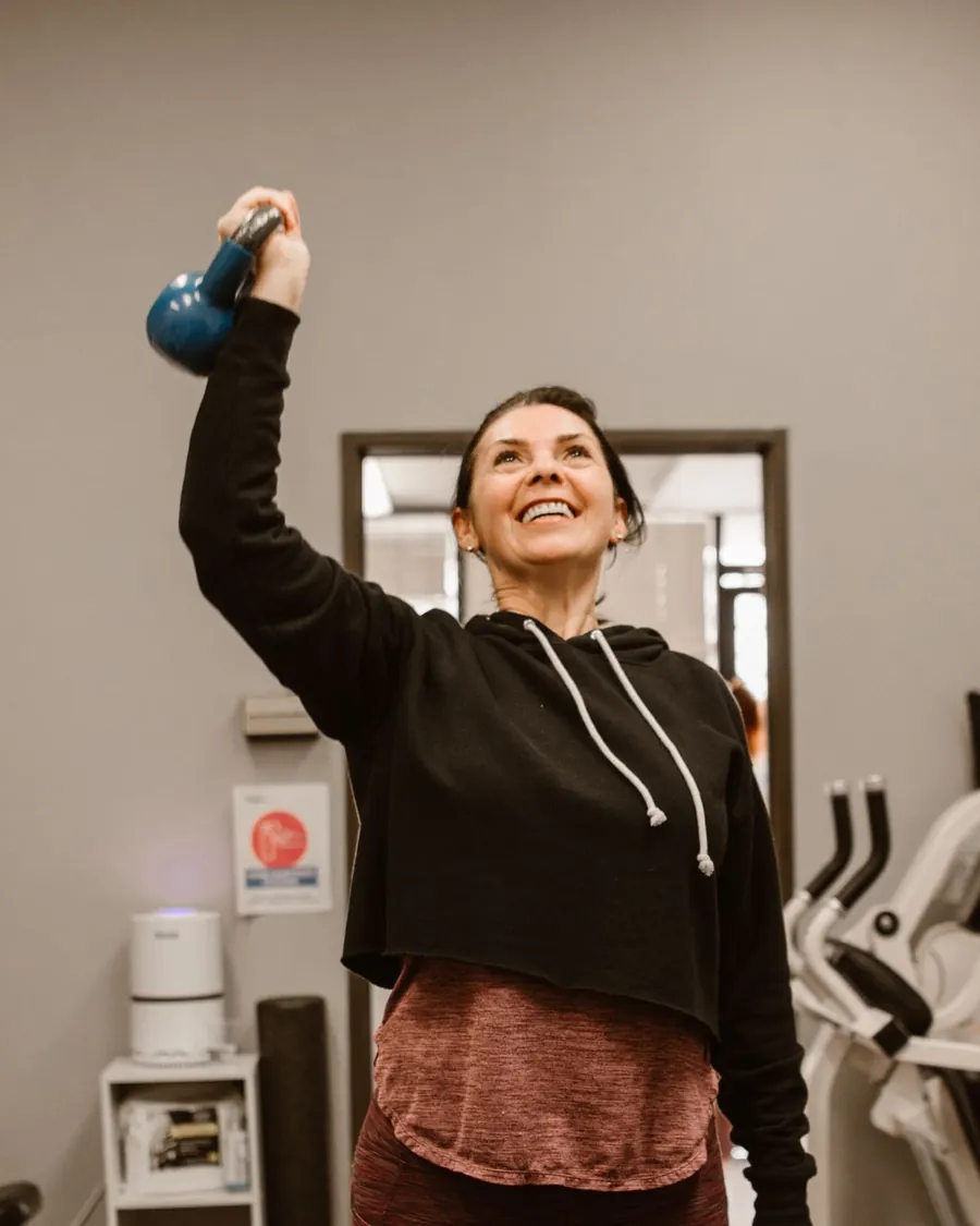 Kobieta wyciska kettlebell nad głowę